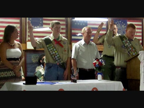 Tayler Vest, flanked by his parents Kellie and Joe Vest, recites the Boy Scout Oath during his Eagle Scout Court of Honor as directed by Eagle Scout Jacob Somers, at podium.