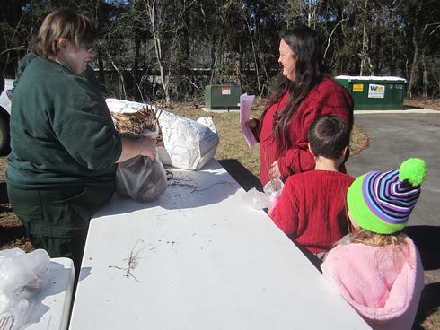 Theresa Herndon, right, receives a bundle of native tree saplings from state Forest Service Senior Forester Maria Wilson as her grandchildren, Iagan and Lexus Foss, observe.