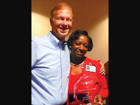 Deidra Faulkner, right, holds her Covenant Hospice Leader of the Year award presented by Odin Berg, the organization's chief financial officer.