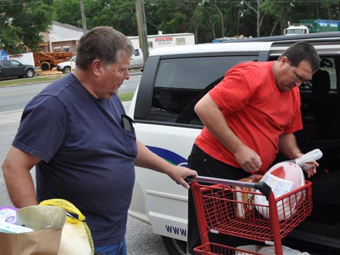 From the left, New Beginnings Church members Tommy Reaves and Jodie Carter load groceries into a taxi for Crestview resident Sandra Bratcher. The men volunteer at the Raymond Williams Mission Center, one of the church's ministries.