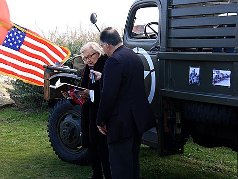 The Rev. Pierre Chatary holds the microphone as Dr. Marie-Thérèse Reed reads a statement during the christening ceremony of a World War II truck.