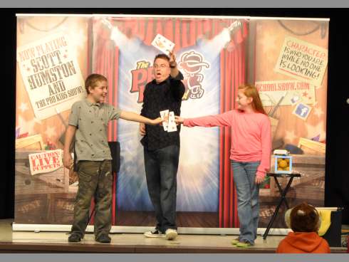 From left, fourth-graders Dryden Triplett and Hayley Steele assist motivational speaker and entertainer Scott Humston with a card trick on Tuesday night at Laurel Hill School.