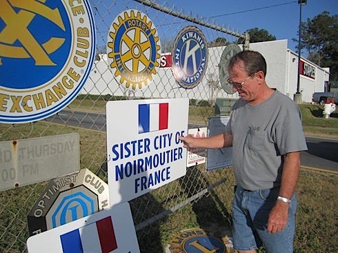 Joe Coffield, a member of Crestview’s Sister City committee, hangs a new sign at the south entrance to town to welcome arriving guests from Noirmoutier, France.