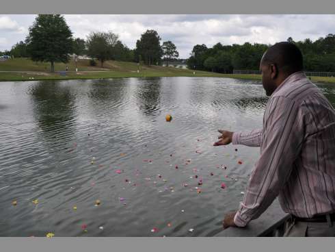 Crestview resident Malcolm Parker tosses a flower into a pond at Twin Hills Park on Sunday following a ceremony presented by Guardian Ad Litem. Attendees tossed flowers in the pond to commemorate children without Guardian Ad Litem representation.