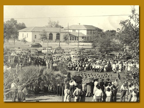 A crowd gathers on the Okaloosa County courthouse lawn for a World War II-era Memorial Day ceremony. Crestview High School, then at the intersection of today's State Road 85 and U.S. Highway 90, is in the background.