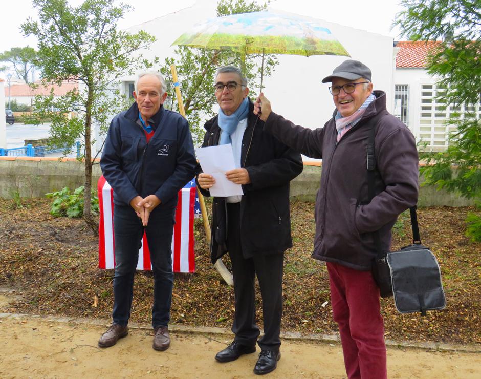 Noirmoutier Sister City Committee treasurer Gérard Moreau holds an umbrella over l’Epine Mayor Dominique Chantoin as town council vice president for education, youth and sports Michel Allemand marks the Dec. 7 planting of a cork oak presented by members of the Crestview Area Sister City Program. [GÉRARD MOREAU/CONTRIBUTED PHOTO]