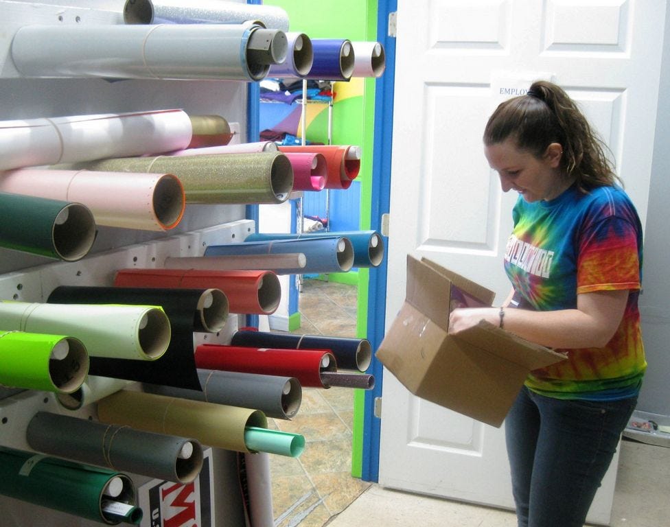 Signs Galore Express manager Kayley Teal-Wibben selects vinyl scraps for a customer to use in her home graphics machine.