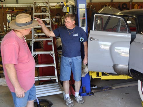 Michael Turman, left, shows Gary Funkhouser how the April 29th floodwaters affected his backyard shop and antique cars.