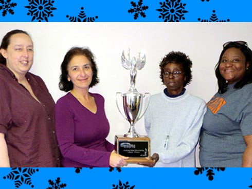 Crestview residents Sheri Mayhair, psychosocial wellness team lead; Brenda Riggleman, supportive housing specialist; Mahalia Simon, transportation and property technician; and Vonetta Parker, PSR specialist hold up the trophy awarded to the holiday door decorating contest winner.