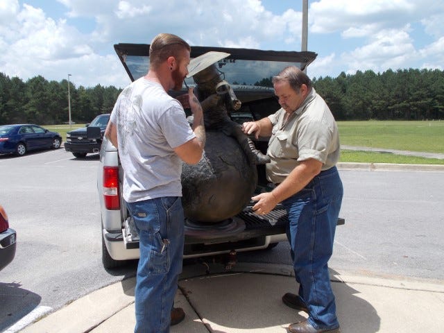 Aaron Charron, owner of AC’s Welding, and his father, Cliff, gently place the Crestview Public Library’s “Whiz Kid” sculpture in their truck on Monday. The men took the recently vandalized bronze sculpture to Baker for restoration.