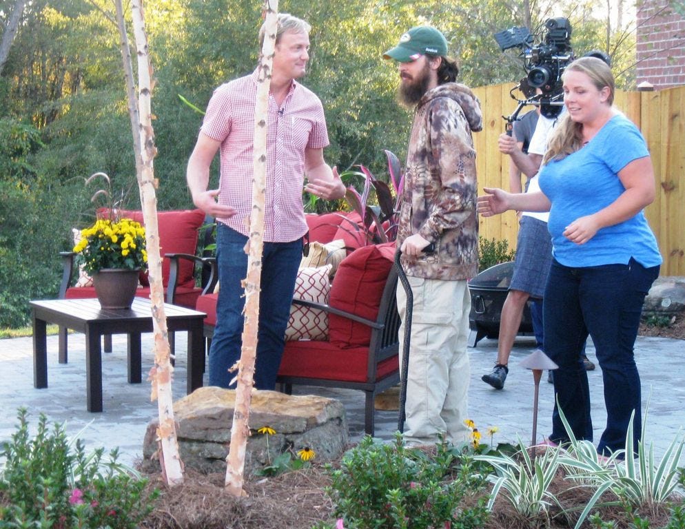 “Designing Spaces” field correspondent Art Edmonds, left, shows Crestview residents Kevin and Tiffany Parke their new patio and koi pond following their home's “Military Makeover.”
