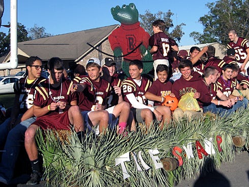 The Baker Gator varsity football team throws candy from a swamp-themed float during the 2013 Baker School Homecoming Parade today near the school entrance.