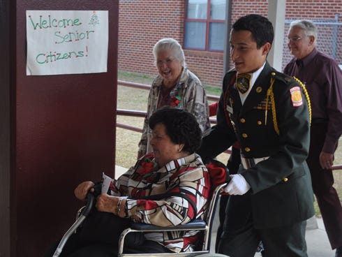 Cadet 1st. Sgt. Javier Steele of the Baker Junior ROTC escorts a senior citizen from the school auditorium to the school cafeteria for a Christmas lunch, during the Senior Citizen's Banquet on Tuesday at Baker school.