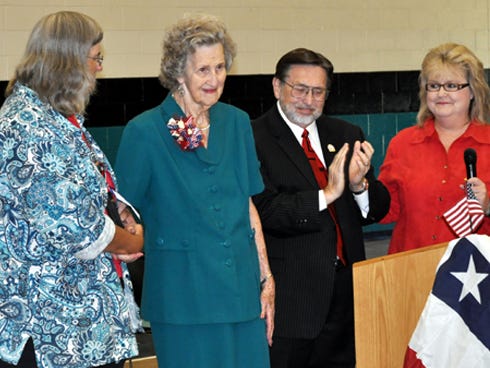 Emily Cassity, center, receives a standing ovation from Davidson Middle School students Friday during a Veterans Day assembly. Crestview Mayor David Cadle — along with Cassity's daughter, Carol, left, and Assistant Principal Kelli Howard — join Emily near the podium.