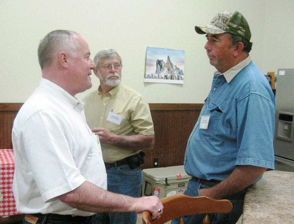 Farm Service Agency administrator Val Dolcini, left, chats with Okaloosa County farmer and FSA county committee chairman Gary Booker, right, as farmer Andy Baber observes.