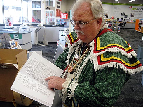 Nathan Chessher, dressed in traditional Creek regalia reflecting his ancestry, reviews the first printing of his local Indian history book.