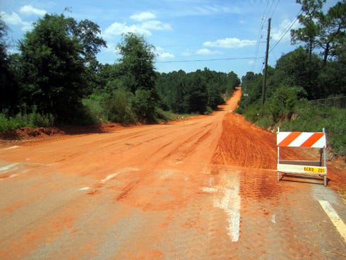 An Okaloosa County Roads Department barricade marks a segment of Okaloosa Lane’s unpaved portion that washed out during recent heavy rains.