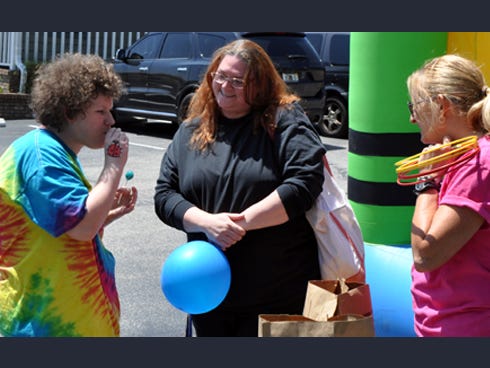 From left, Jessica Sollie, 16, blows into a toy whistle while her mother Andrea Franklin, center, and therapist Mary Seidenfaden look on.