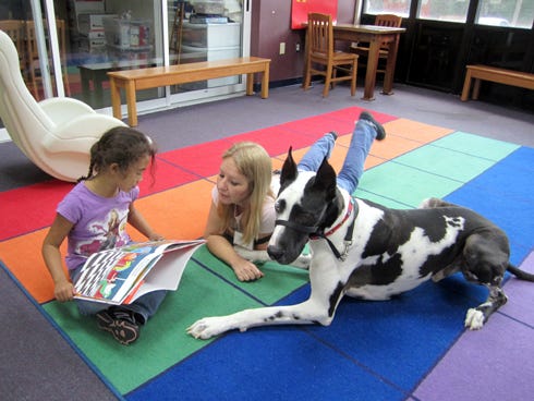 With Angie Nousiainen's help, Tashana Striegel, then 5, reads a book to Dozer the Therapy Dog at the Crestview Public Library last year. Dozer is now also a greeter at Walgreen's.