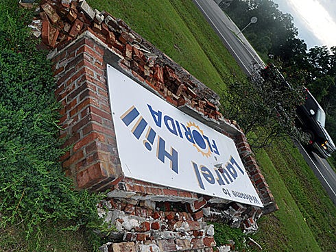 The "Welcome to Laurel Hill Florida" sign rests beside State Road 85 following a hit and run and strong winds that led to its demise. The city plans to replace the sign, which is insured for up to $10,000, city clerk Nita Miller said.